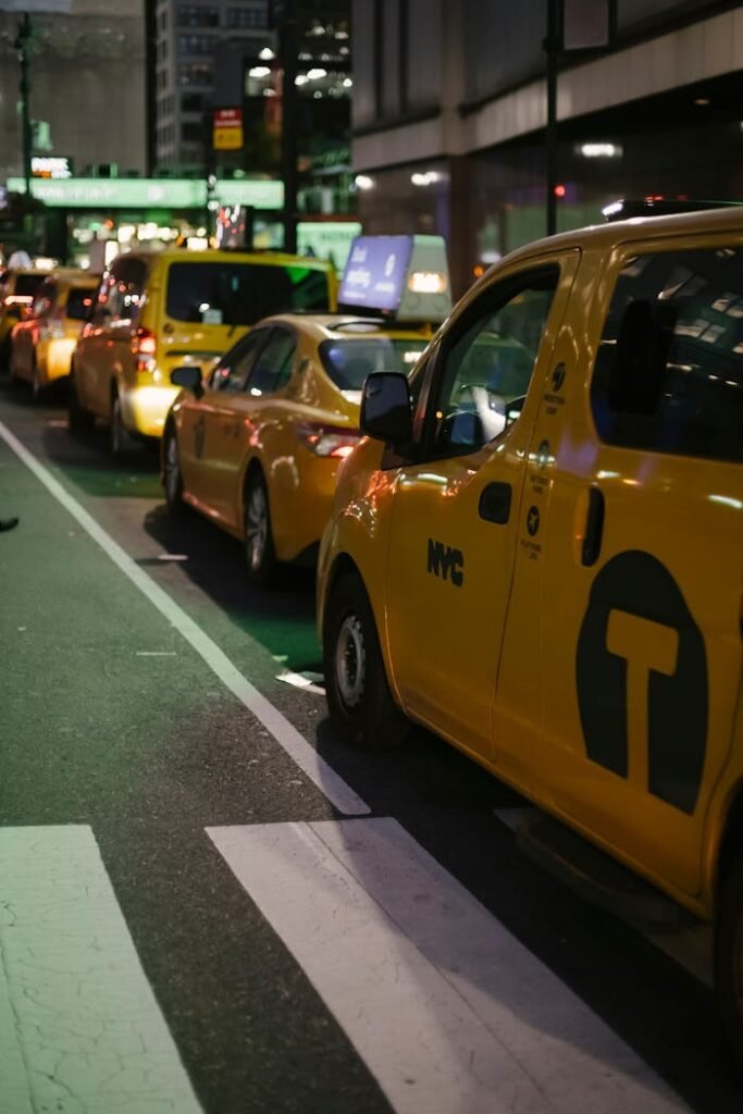 Yellow taxis line a bustling street in New York City at night, illuminating the urban landscape.