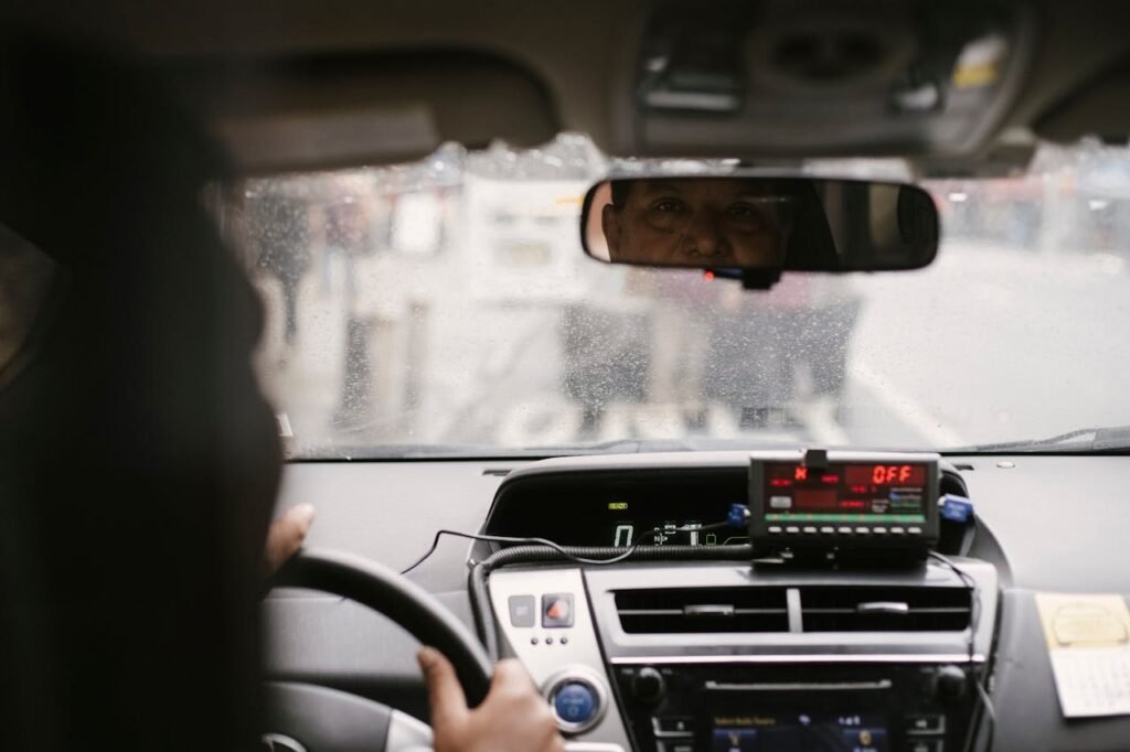 Back view of man reflecting in mirror while driving along street in city on urban background in soft daylight